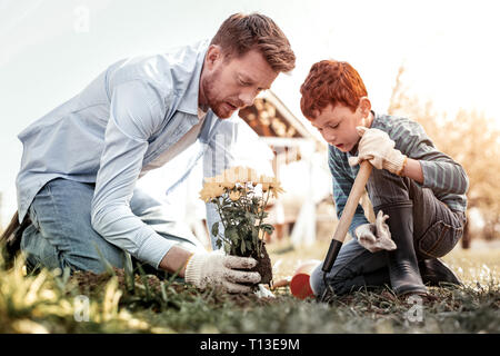 Piccoli i capelli rossi gentleman utilizzando la pala durante il giardinaggio Foto Stock