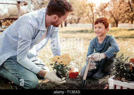Padre responsabilità di insegnamento in modo che mostra come piantare fiore Foto Stock