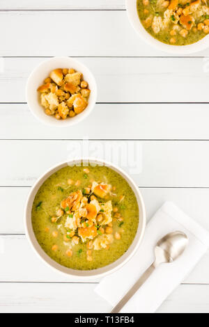 Due ciotole di broccoli e la zuppa di ceci con un condimento di cotta al forno a ciabatta pane grattugiato mescolato con parmigiano e decorate con il crescione. Vista superiore Foto Stock