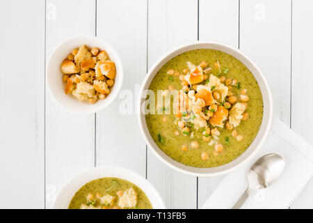 I broccoli e la zuppa di ceci con un condimento di cotta al forno a ciabatta pane grattugiato mescolato con parmigiano e decorate con il crescione. Vista dall'alto. Foto Stock