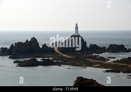La Corbiere Lighthouse sorge su uno sperone roccioso di marea collegata alla terraferma da una strada rialzata sull'isola di Jersey, nelle Isole del Canale, UK. Foto Stock