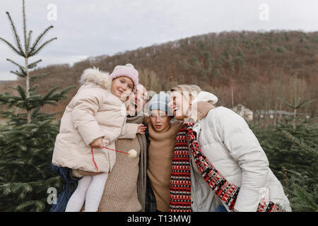 Ritratto di famiglia felice con due bambini su un albero di Natale di piantagione Foto Stock