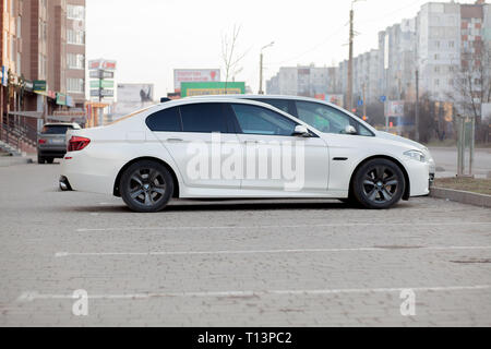 Kiev, Ucraina - 27 Febbraio 2019: vista laterale del bianco auto parcheggiate nel parcheggio asfaltato area sul sobborgo sfocate su strada su sfondo luminoso giorno. Trans Foto Stock