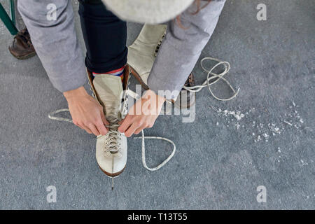 Donna puuting sui suoi pattini da ghiaccio, vista da sopra Foto Stock