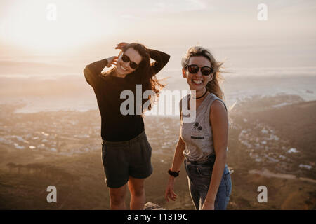 Sud Africa, Cape Town, Kloof Nek, ritratto di due felici donne al tramonto Foto Stock