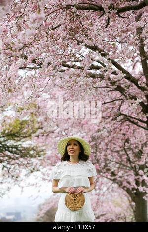 Londra, Regno Unito. 22 Mar, 2019. Una donna si vede nella parte anteriore dei fiori di ciliegio in North London park. Credito: Dinendra Haria/SOPA Immagini/ZUMA filo/Alamy Live News Foto Stock