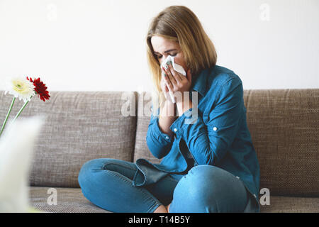 La molla di freddo o di allergie. Una giovane ragazza attraente è allergico ai fiori, utilizza un tovagliolo a casa Foto Stock