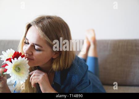 Attraente giovane donna lo sniffing bouquet di fiori sdraiato sul lettino Foto Stock