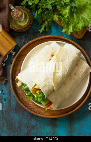 Un sano pranzo snack. Tortilla avvolge con pollo alla griglia e verdura fresca sul tavolo blu. Pollo Tortilla messicana street fast food. Copia dello spazio. Foto Stock
