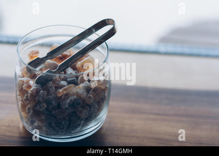 Zucchero di canna cristalli in una ciotola di vetro su di un tavolo di legno Foto Stock