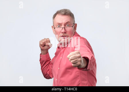 Uomo in camicia rossa in piedi in posa boxer con pugni sollevata come se la difesa Foto Stock