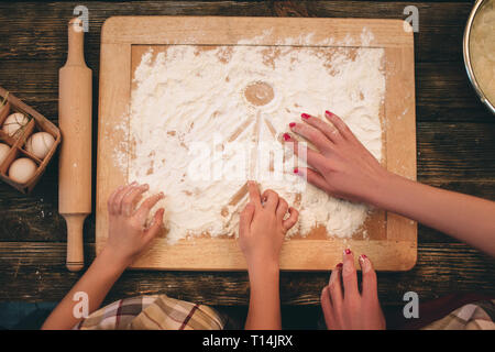 Famiglia la cottura di torte fatte in casa, la mamma e figlia 's mani nella farina su un sfondo tabella Foto Stock