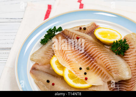 Il coregone di pesci di Tilapia filetto crudo su sfondo di legno. Messa a fuoco selettiva. Foto Stock