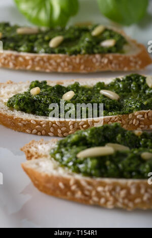 Bruschetta con pesto di basilico sauace e pinoli, su una piastra bianca. Cibo sano, la dieta e il concetto di cucina a vista. Specialità della cucina italiana. Sof selettiva Foto Stock