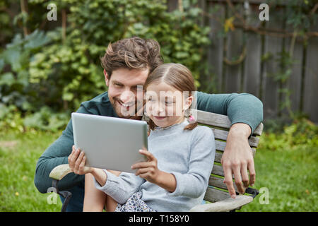 Felice padre e figlia utilizzando tablet insieme in giardino Foto Stock