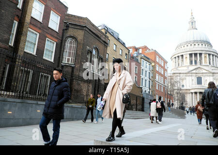 Un elegante turistici cinesi giovane camminando verso il Millennium Bridge al di fuori di St Pauls Cathedral nella città di Londra UK KATHY DEWITT Foto Stock