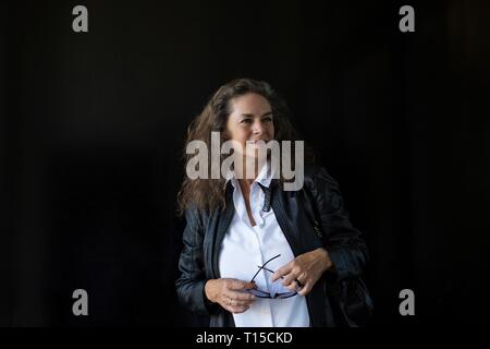 Sorridente donna matura abbigliamento in pelle nera e camicia bianca di fronte a sfondo nero Foto Stock