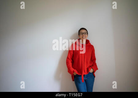 Ritratto di un sorridente giovane donna con capelli corti, pendente a parete Foto Stock