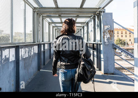 Vista posteriore della giovane donna a camminare su un ponte Foto Stock