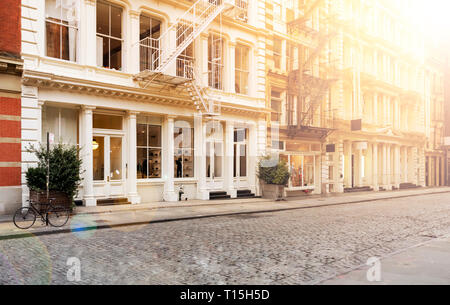 La luce del sole splende sul vuoto lungo i marciapiedi coperti in ciottoli di Greene Street nel quartiere di SoHo di Manhattan a New York City NYC Foto Stock