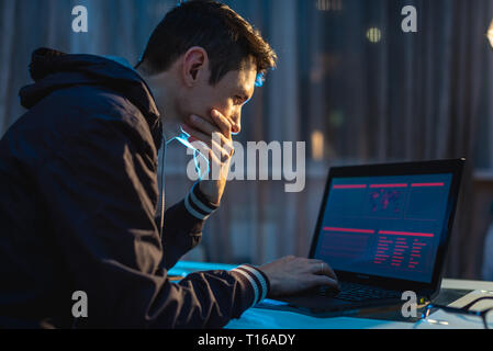 Un maschio di hacker a pensare al problema della pirateria e il furto di accedere ai database con password. Il concetto di sicurezza informatica Foto Stock