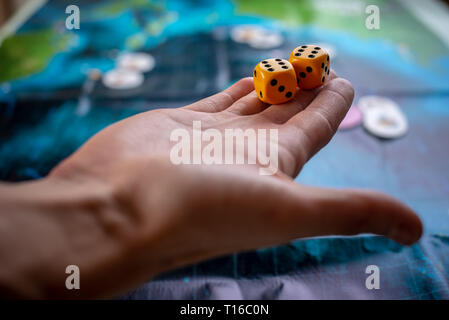 La mano lanci di dadi di colore giallo sul campo di gioco. Buona fortuna e le emozioni. Il concetto dei giochi da tavolo Foto Stock