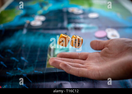 La mano lanci di dadi di colore giallo sul campo di gioco. Buona fortuna e le emozioni. Il concetto di giochi da tavolo. Momenti di gioco nella dinamica Foto Stock