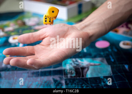 La mano lanci di dadi di colore giallo sul campo di gioco. Buona fortuna e le emozioni. Il concetto dei giochi da tavolo Foto Stock