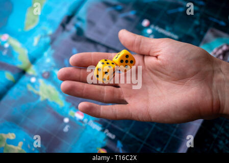 La mano lanci di dadi di colore giallo sul campo di gioco. Buona fortuna e le emozioni. Il concetto dei giochi da tavolo Foto Stock