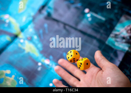 La mano lanci di dadi di colore giallo sul campo di gioco. Buona fortuna e le emozioni. Il concetto dei giochi da tavolo Foto Stock