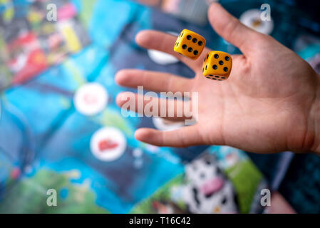 La mano lanci di dadi di colore giallo sul campo di gioco. Buona fortuna e le emozioni. Il concetto di giochi da tavolo. Momenti di gioco nella dinamica Foto Stock