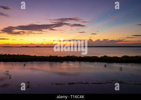 Il sole tramonta sulla Baia di Chetumal off Ambergris Caye Belize casting brillanti tonalità attraverso il cielo e riflettendo nelle acque increspata da una brezza calda. Foto Stock