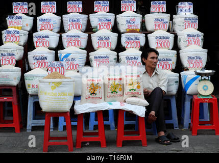 Il vietnamita venditore sedersi al negozio di riso di outdoor mercato contadino, molti sacchetto di riso con i cartellini del prezzo di mercato del prodotto di agricoltura, a Saigon, Vietnam Foto Stock