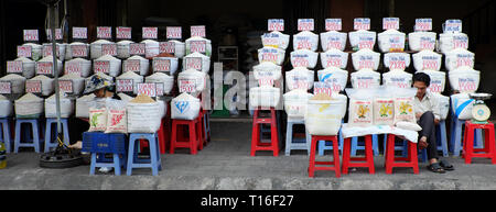 Il vietnamita venditore sedersi al negozio di riso di outdoor mercato contadino, molti sacchetto di riso con i cartellini del prezzo di mercato del prodotto di agricoltura, a Saigon, Vietnam Foto Stock