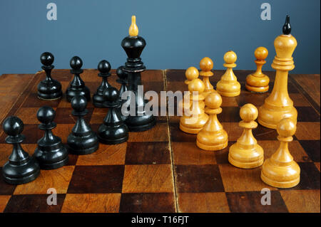 Leader vs boss o manager. Re di scacchi e pedine sulla scrivania. Foto Stock