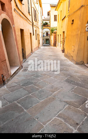 Chiusi, Italia strada vuota nel piccolo villaggio di città in Toscana stretta vista verticale durante il giorno con giallo arancio luminoso vibranti colori vivaci pareti closeup Foto Stock