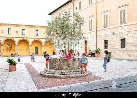 Chiusi, Italia - 25 agosto 2018: Via Piazza dalla chiesa nel piccolo villaggio di città in Umbria durante il giorno con i bambini persone i bambini giocando da cisterna romana Foto Stock