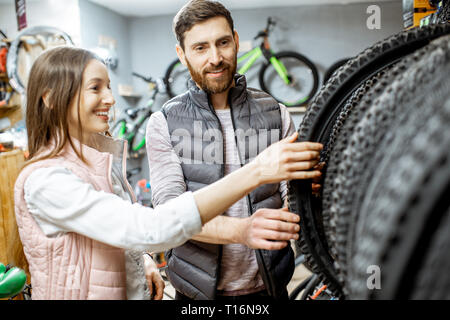 Venditore aiutare giovani donne a scegliere un nuovo pneumatico di una bicicletta nel negozio di articoli sportivi Foto Stock