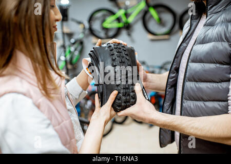 Donna prendendo un nuovo pneumatico per bicicletta e acquisto di alcune parti di biciclette nel negozio di articoli sportivi, vista da vicino Foto Stock