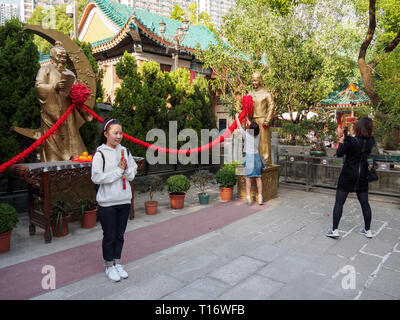 Kowloon, Hong Kong - 03 Novembre 2017: una donna pone di fronte alla statua di Yue Lao in Wong Tai Sin temple di Hong Kong. Foto Stock