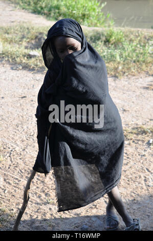 IGUNGA, Tanzania - 6 febbraio 2012: un bambino della tribù Wataturu appoggiato su un bastone. Foto Stock