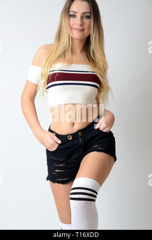 Montare la ragazza da Polonia con ventre scoperto. Giovane femmina modello con grande forma bianco da indossare top, pantaloncini neri e calze. Foto Stock