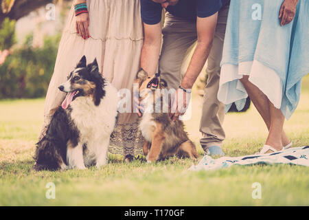 Gruppo di famiglia con i cani. Tre popoli caucasici in giardino godendo del tempo trascorso con due cani Foto Stock