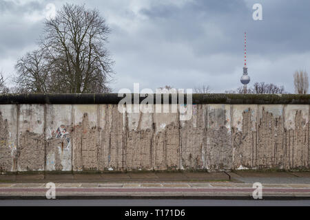Vista frontale di una sezione originale del muro di Berlino al Memoriale del Muro di Berlino (Berliner Mauer) di Berlino. Fernsehturm Torre della TV è in background. Foto Stock