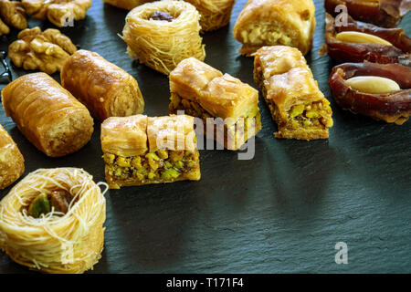 Tipo diverso di arabian baklava su sfondo nero con spazio per i tipi di testo - nido borma ush-el-bul-bul asabi Foto Stock