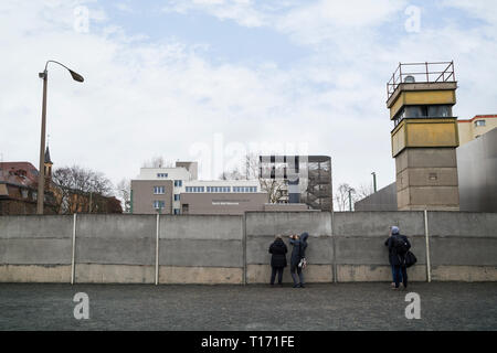 Le persone al Memoriale del Muro di Berlino (Berliner Mauer) di Berlino, Germania. Torre di vedetta si trova dietro il muro di Berlino. Centro di documentazione è in backgroun Foto Stock