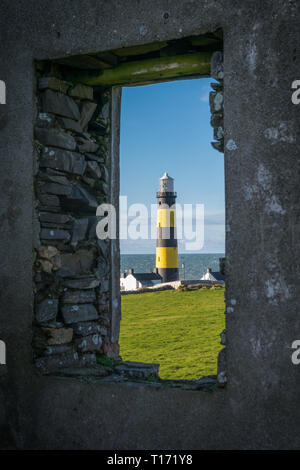 Questa è una foto di St John's Point Lighthouse attraverso una finestra delle rovine di una vecchia stazione di guardia costiera sulla costa orientale dell'Irlanda del Nord su t Foto Stock