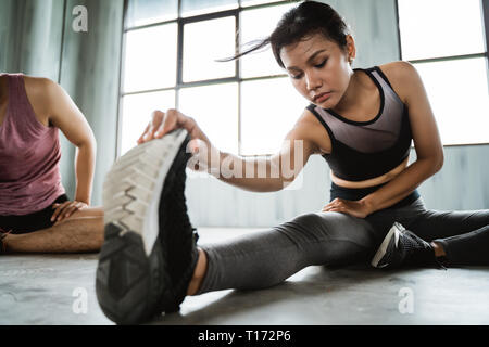 Donna sportivo facendo stretching gambe Foto Stock