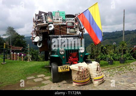 Visualizzazione di una Jeep Willy sovraccarica di articoli casalinghi e battenti la bandiera colombiana, il Salento, Colombia Foto Stock