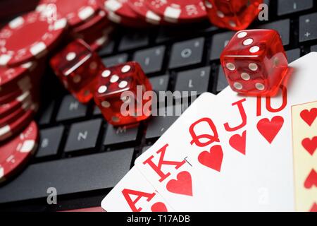 Casino chips, schede e dadi impilare su un computer portatile Foto Stock